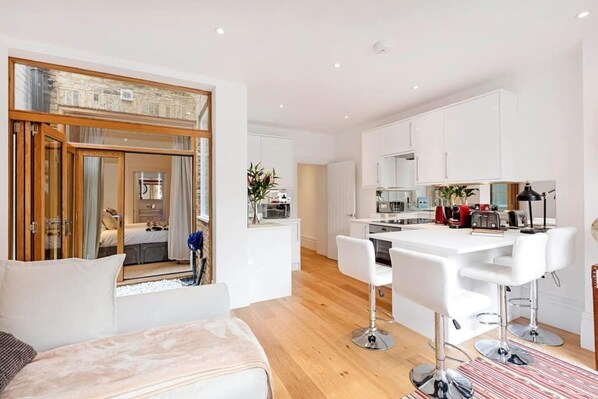 Een modern appartement met een grote spiegel, een eethoek, een keuken en een woonkamer.