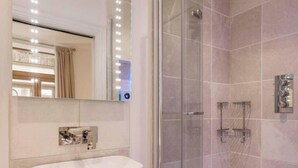 Een moderne badkamer met een douche met glazen wand, een wastafel met spiegel en een bad.