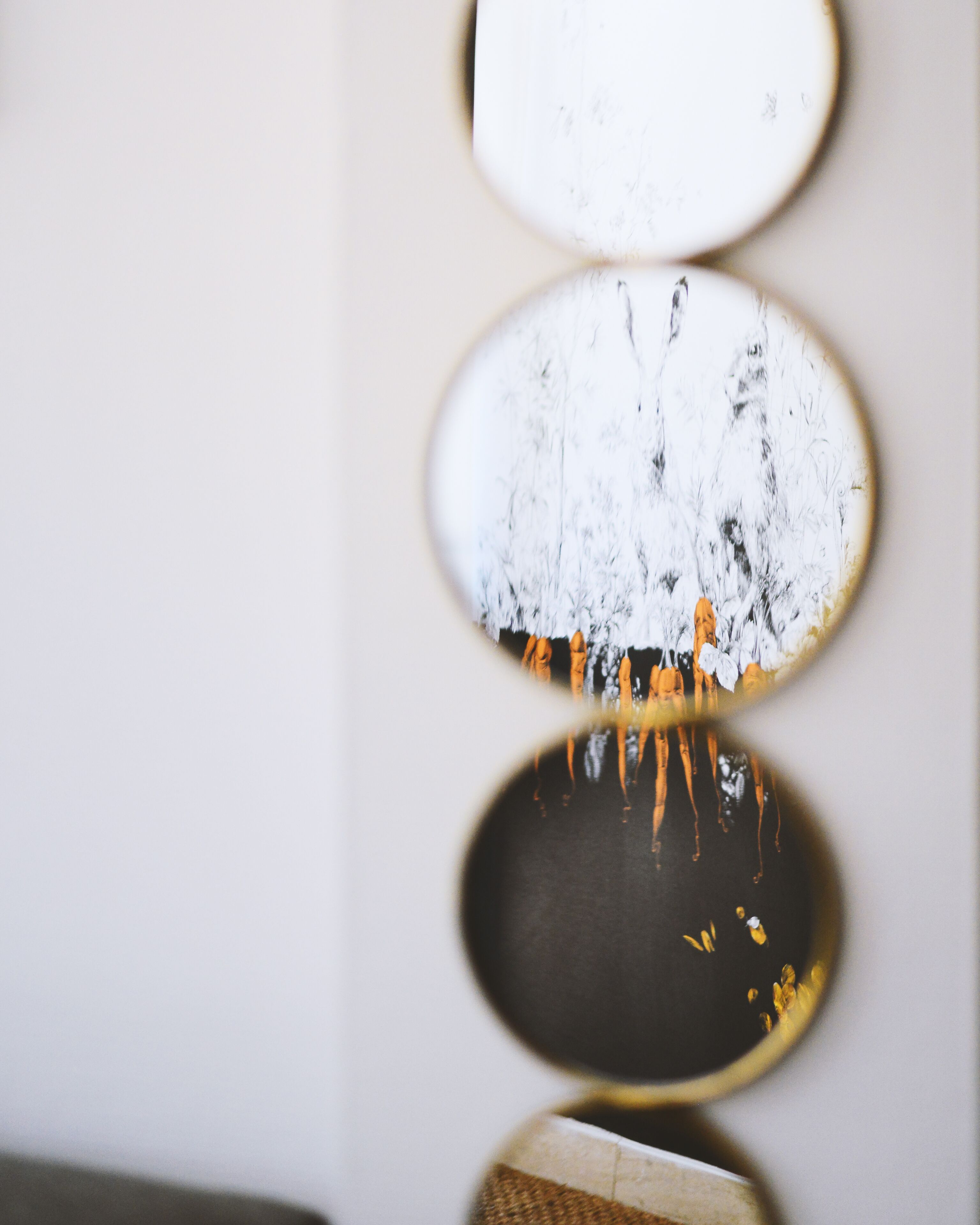 Un mur orné de trois miroirs circulaires de tailles différentes.