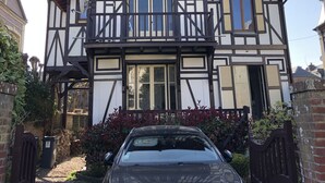 Un immeuble de deux étages, de style architectural traditionnel, doté d’un balcon et avec une voiture garée devant.