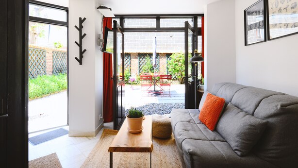 Un salon moderne avec un canapé gris, une table basse en bois et une plante en pot.