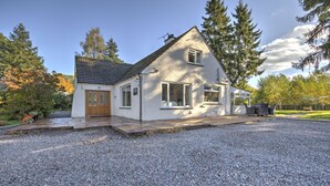 Een huis met twee verdiepingen, een grindpad, een voortuin en een klein terras.