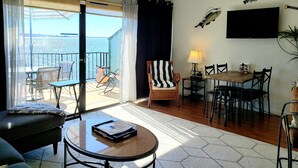 Une chambre avec balcon, un coin repas et un espace salon comprenant une table et des chaises.