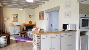 A cozy living room with a fireplace, a dining area, and a kitchen with modern appliances. - Cocooning bubble and immersive veranda in a green setting 100m from the beach (Varaville)