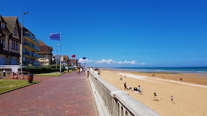 A seaside promenade with a brick pathway, beach, and buildings with balconies. - Cocooning bubble and immersive veranda in a green setting 100m from the beach (Varaville)