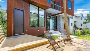 A modern house with a wooden deck, large windows, and a balcony. - Makai House | Tranquil Folly Retreat (Folly Beach)