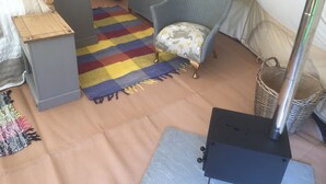 A tent with a bed, a chair, a small table, a colorful rug, and a portable stove. - Glamping at The Homestead - Ensuite Bell Tent (Hereford)
