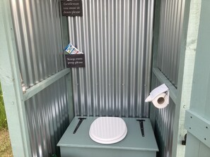 En mobilt toilet med toilet, håndvask og toiletpapirholder.