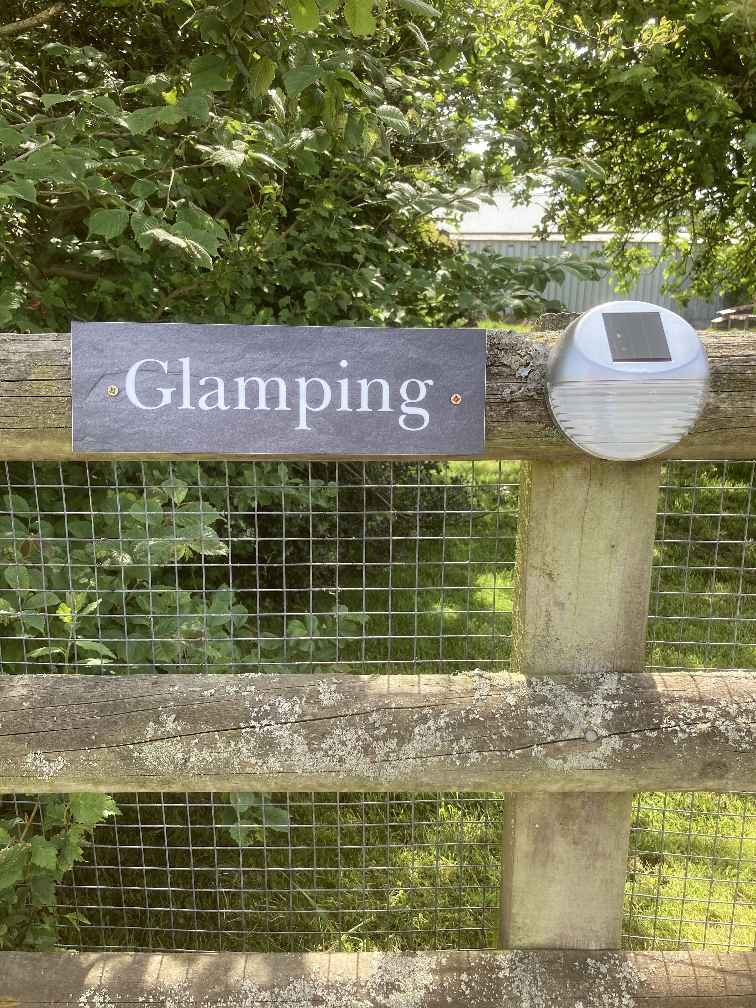 A wooden fence with a sign that reads "Glamping."