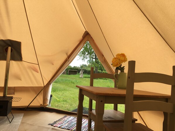 Een tent met een tafel en stoelen, een lamp en een vaas met bloemen.