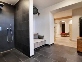 Un baño moderno con ducha, una banca y una camilla de masaje.