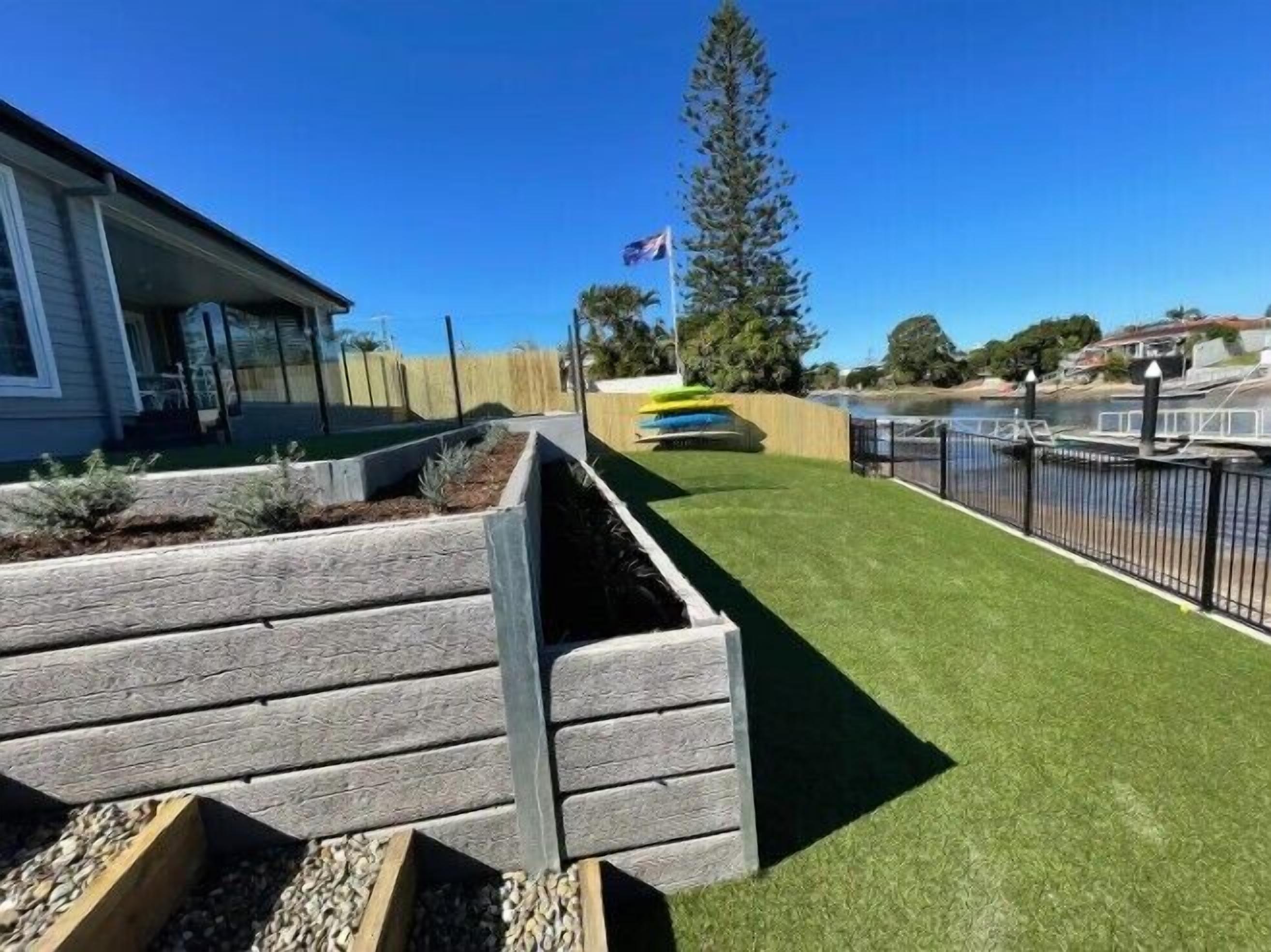 A residential property with a well-maintained lawn, a wooden deck, and a view of a body of water.