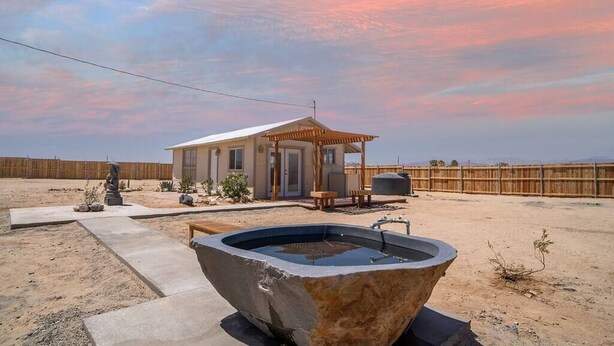 A desert-style house with a patio, outdoor seating, and a hot tub.
