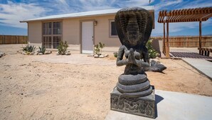 A desert landscape with a building featuring a large window and a statue in front.