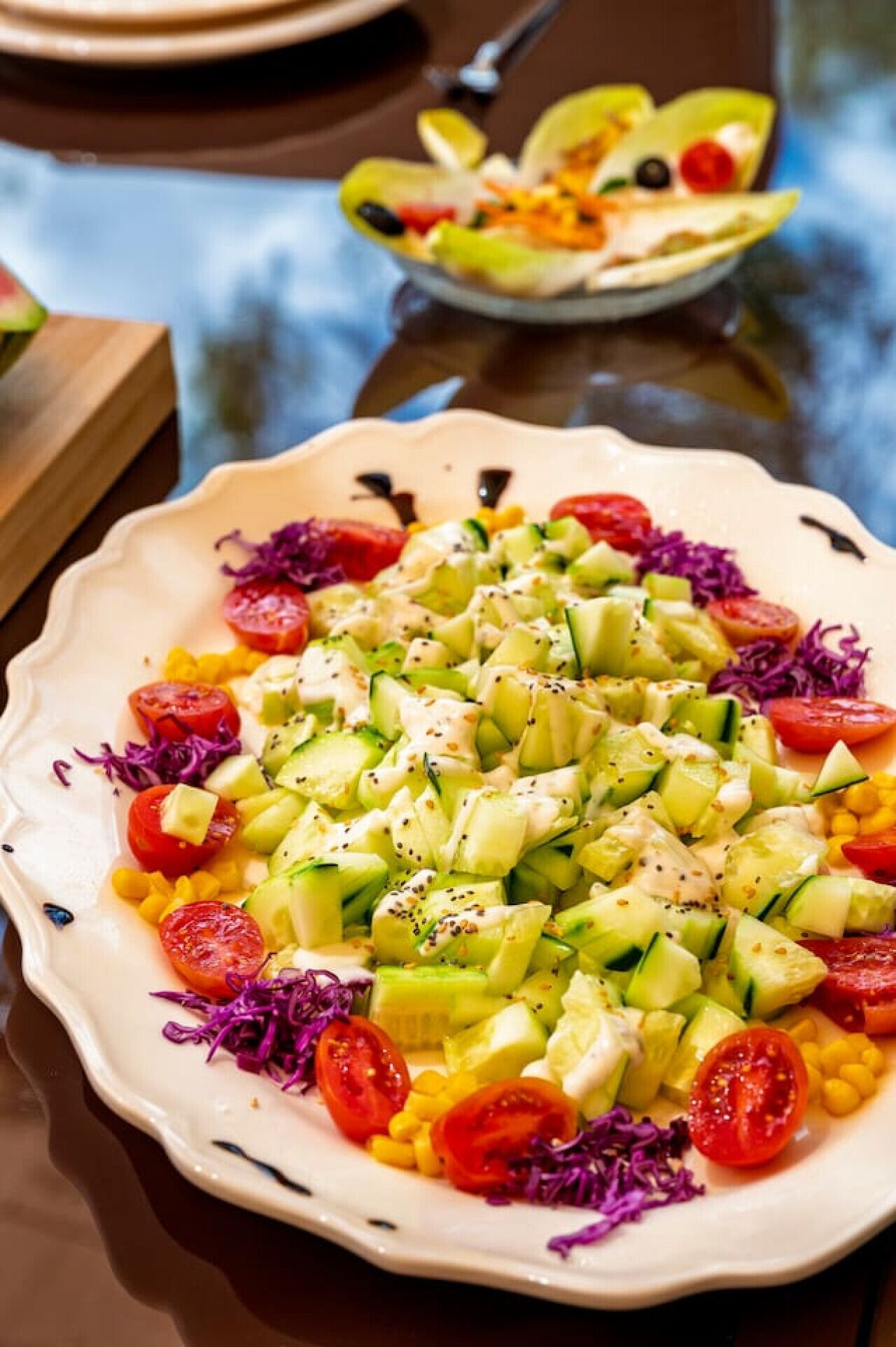A plate of colorful salad with various vegetables and a creamy dressing.