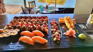 Una bandeja de sushi sobre una mesa, con vista al puerto y edificios al fondo.