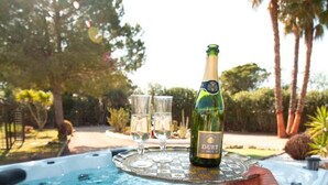 Un jacuzzi con una botella de champán Duet y dos copas sobre una bandeja.