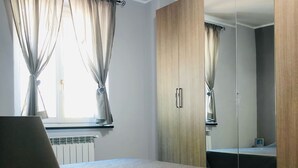 A bedroom with a bed, a bedside table with a lamp, a window with curtains, and a wardrobe with a mirror. - Gorgeous apartment with large sea view terrace (Civezza)