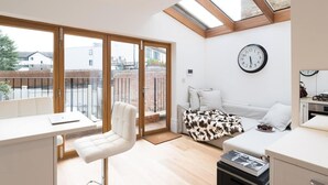A modern apartment with a balcony, a sofa, a dining area, and a kitchen.