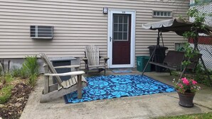 A house exterior with a front door, a porch with a blue patterned rug, a wooden chair, and a potted plant. - A quiet place near Ithaca, Ithaca College & Cornell. (Danby)