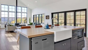 A modern kitchen with a large island, built-in appliances, and large windows offering a view of the outdoors. - Magnificent Chalet, Sweeping Views and Hot Tub (Ellicottville)