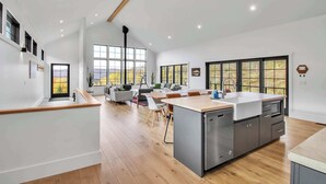 A modern kitchen with a central island, built-in appliances, and large windows. - Magnificent Chalet, Sweeping Views and Hot Tub (Ellicottville)