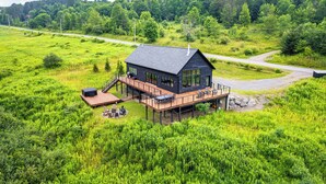 A modern house with a deck, surrounded by lush greenery. - Magnificent Chalet, Sweeping Views and Hot Tub (Ellicottville)