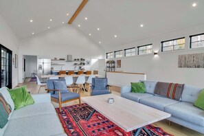 A spacious living area with a sofa, chairs, a coffee table, and a dining area in the background. - Magnificent Chalet, Sweeping Views and Hot Tub (Ellicottville)
