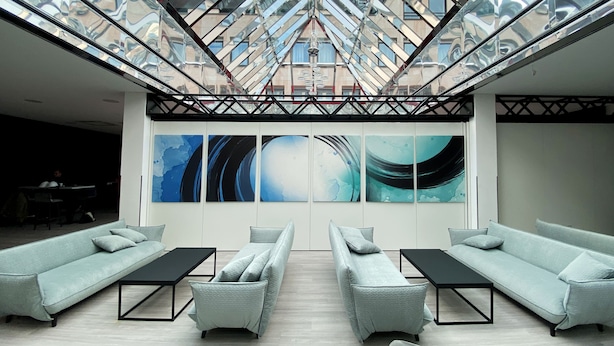 A modern lounge with a glass ceiling, light grey sofas, and abstract wall art. - DORMERO Hotel Hersbruck (Hersbruck)