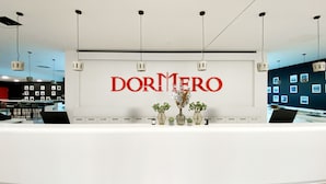 A reception desk with a 'DORMERO' sign, a modern interior, and a wall with framed pictures. - DORMERO Hotel Hersbruck (Hersbruck)