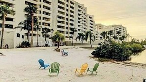 A beach with several colorful chairs and a large hotel building in the background.