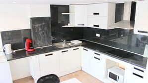 A modern kitchen with white cabinets, a black countertop, and a microwave. - DUPLEX Impressionnistes Barbizon Rive Gauche (Barbizon)