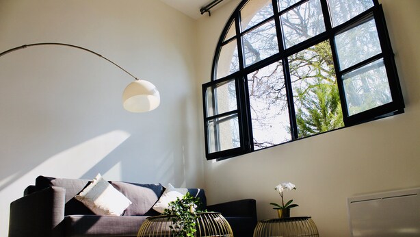 A modern living room with a sofa, a large window, and two spherical vases. - DUPLEX Impressionnistes Barbizon Rive Gauche (Barbizon)
