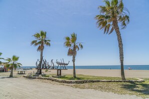 Ein Strand mit Palmen, einer Skulptur und einer Bank.