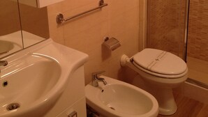 A bathroom with a sink, bidet, toilet, and a glass shower enclosure. - CASA PETRA - OPEN SPACE (brindisi)