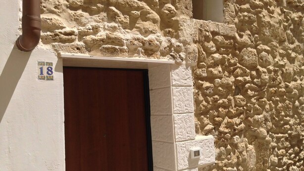 A stone wall with a wooden door and a number plate indicating room 18. - CASA PETRA - OPEN SPACE (brindisi)