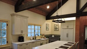 A kitchen with white cabinets, a large island, a stove, and a sink. - Gorgeous Home and Property Located Just 30 Minutes From Glacier National Park (Kalispell)