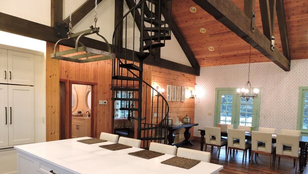 A spacious kitchen with a central island, wooden beams, and a spiral staircase. - Gorgeous Home and Property Located Just 30 Minutes From Glacier National Park (Kalispell)