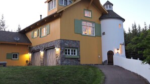 A large, two-story house with a stone foundation, a tower, and a covered garage. - Gorgeous Home and Property Located Just 30 Minutes From Glacier National Park (Kalispell)
