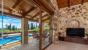 Un grand balcon doté d’une cheminée en pierre, d’une piscine et d’un téléviseur.