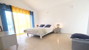 A bedroom with a bed, bedside tables, a dresser, and a suitcase.