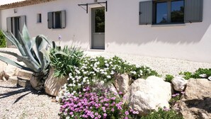 A white building with a tiled roof, a door, and windows with shutters.