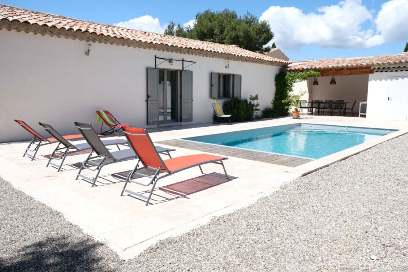A swimming pool with lounge chairs and a covered patio area.