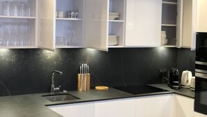 Eine moderne Küche mit weißen Schränken, einer schwarzen Arbeitsplatte und einem eingebauten Backofen.