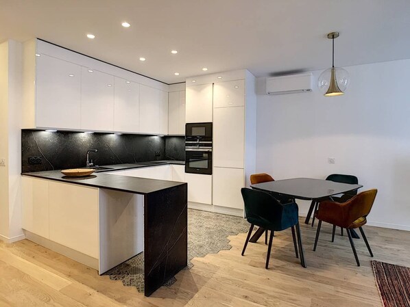 Une cuisine moderne dotée d’un îlot central, de meubles blancs et d’un coin repas avec une table et des chaises.