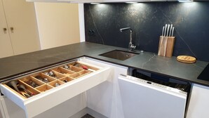 Eine Küche mit schwarzem Arbeitsplatz, integriertem Spülbecken und Geschirrspüler.