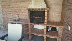 Une cuisine extérieure en briques, dotée d’un évier et d’un barbecue.