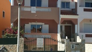 Un immeuble de deux étages avec un balcon, une pancarte indiquant qu’il est à louer et un lampadaire.
