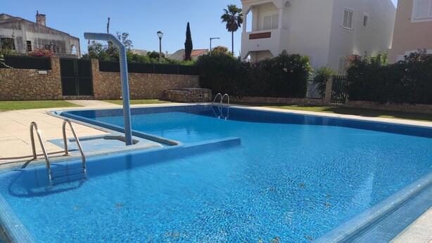 Une piscine rectangulaire à l’eau d’un bleu limpide, entourée d’un mur de pierre et dotée d’une échelle en métal.