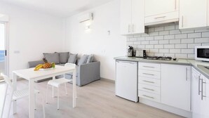 Une cuisine moderne avec des meubles blancs, un four à micro-ondes encastré et un lave-vaisselle compact.